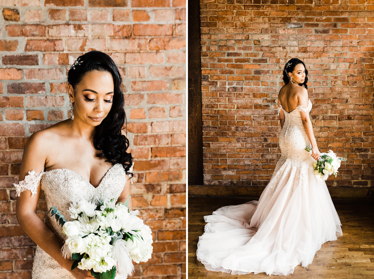 bride's long train from her mermaid wedding dress pool on wooden floor. she stands at brick wall and looks over her shoulder