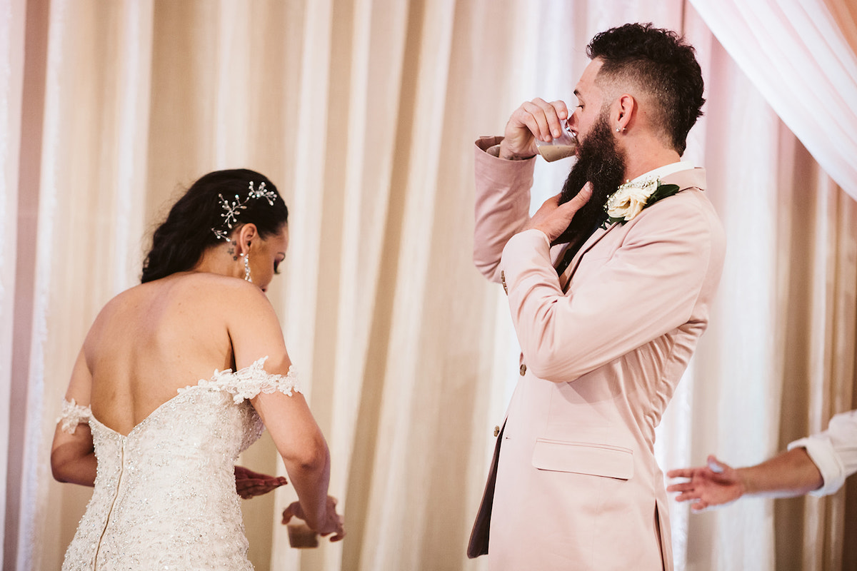 bride and groom toast each other while officiant presents reading