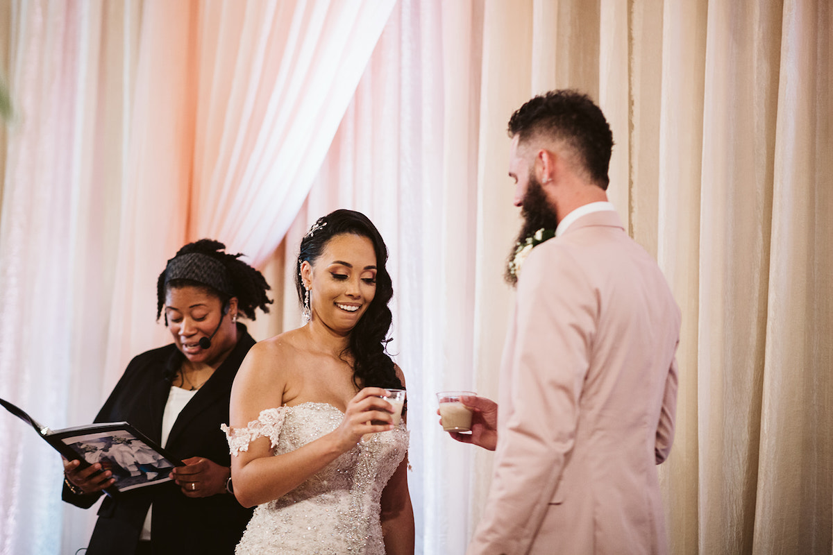 bride and groom toast each other while officiant presents reading
