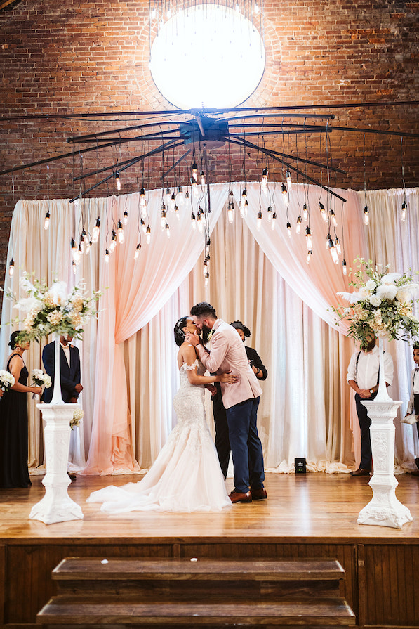 bride and groom kiss under large round window at The Church on Main wedding ceremony in Chattanooga