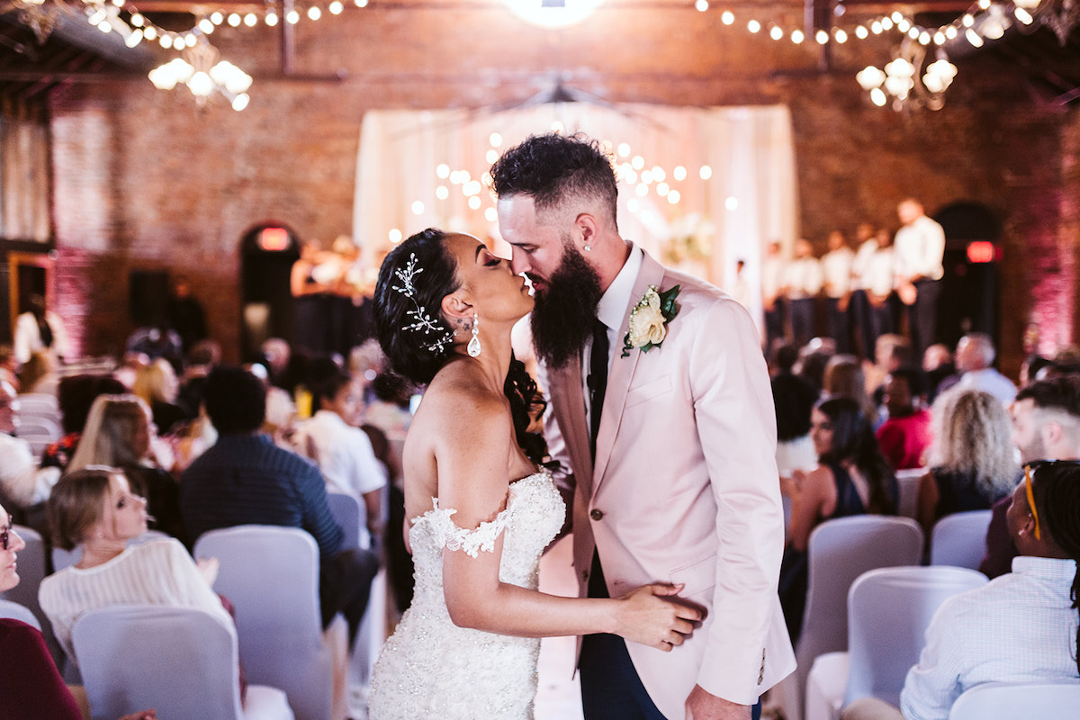 bride and groom stop for a kiss at the end of the aisle after their wedding at The Church on Main in Chattanooga Tennessee