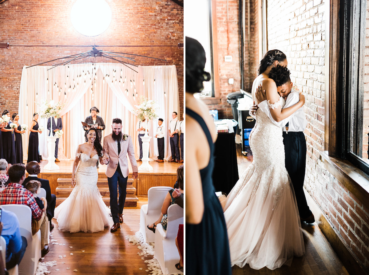 bride hugs young boy next to a brick wall and large window