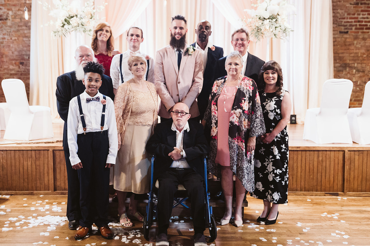 Groom stands with family members for family photo