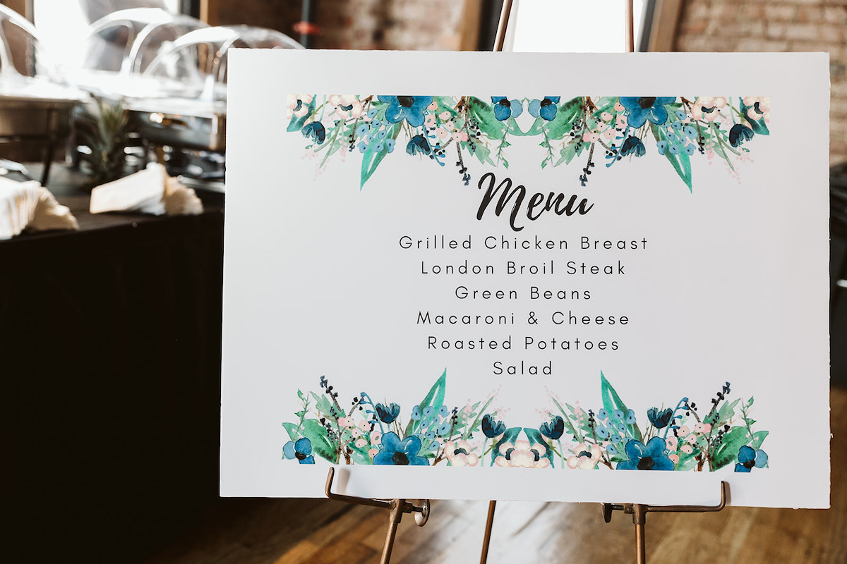 Printed Menu sign announces meal choices next to a black, draped buffet table