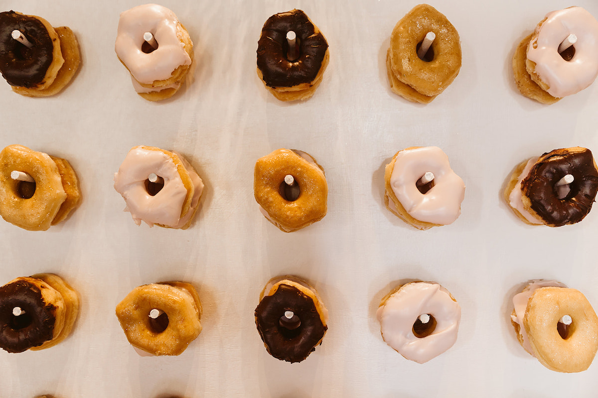 mixed donuts hang on dowels on a wall
