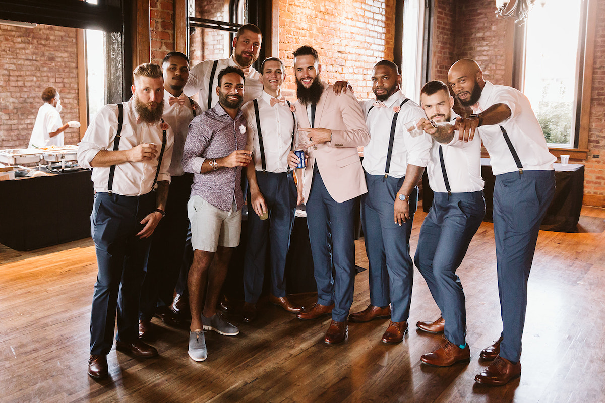 groom and groomsmen pose together near buffet tables at The Church on Main wedding reception