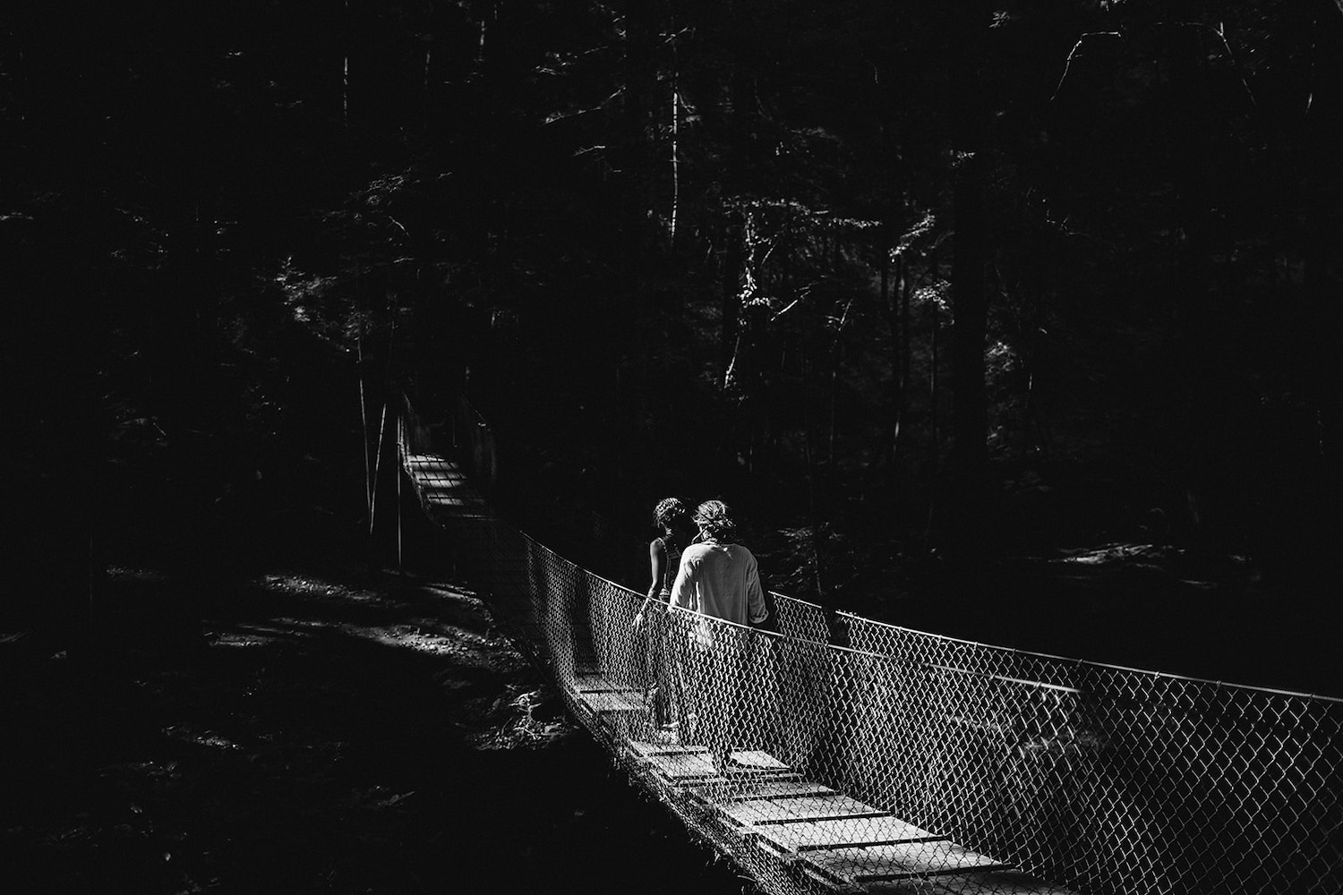 man and woman cross a wooden suspension bridge toward Foster Falls in Chattanooga, TN for bride and groom portraits