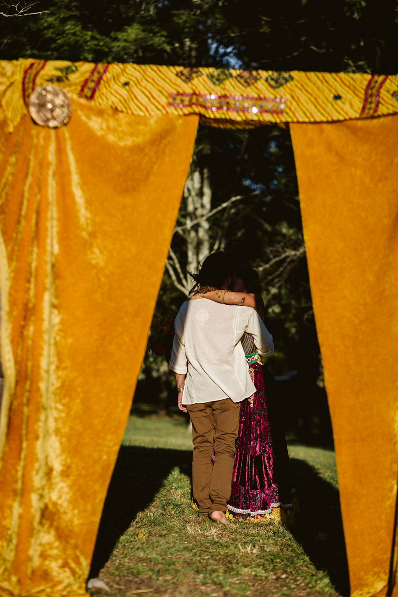 man and woman hug behind orange-gold curtain