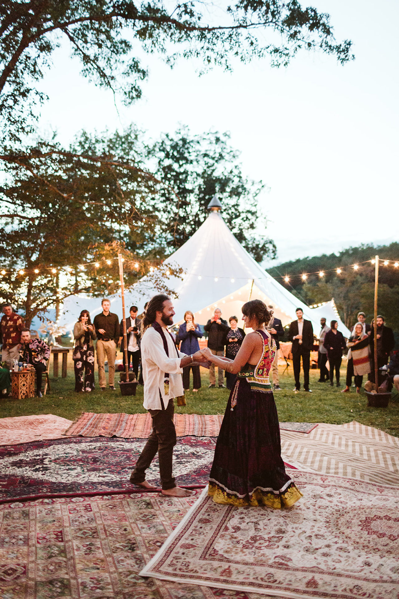 man and woman dance on outdoor dance floor made of Oriental rugs and their Bohemian festival wedding reception in Chattanooga