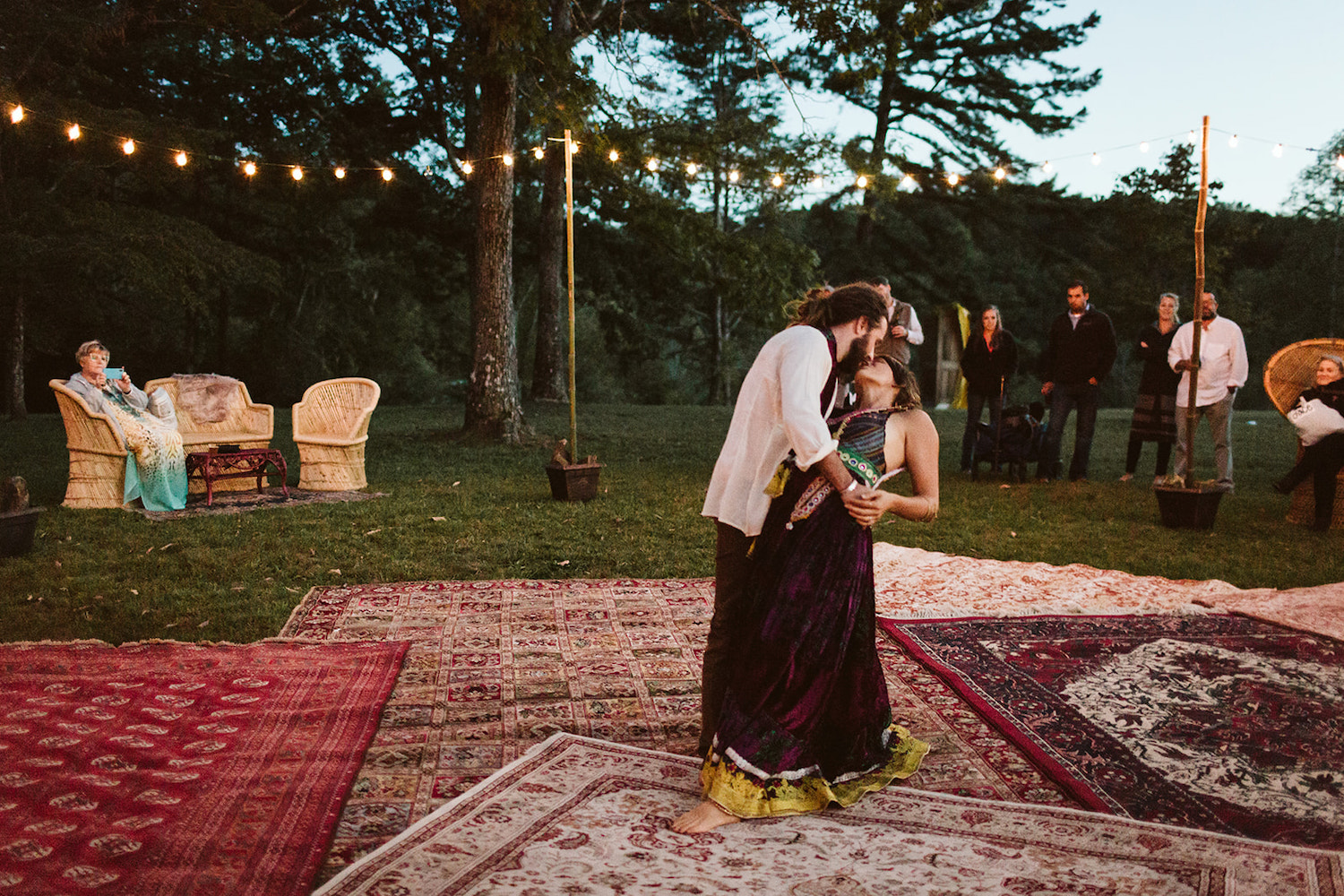 man dips woman as they dance on Oriental run outdoor dance floor at their Hemlock Falls Bohemian festival wedding reception