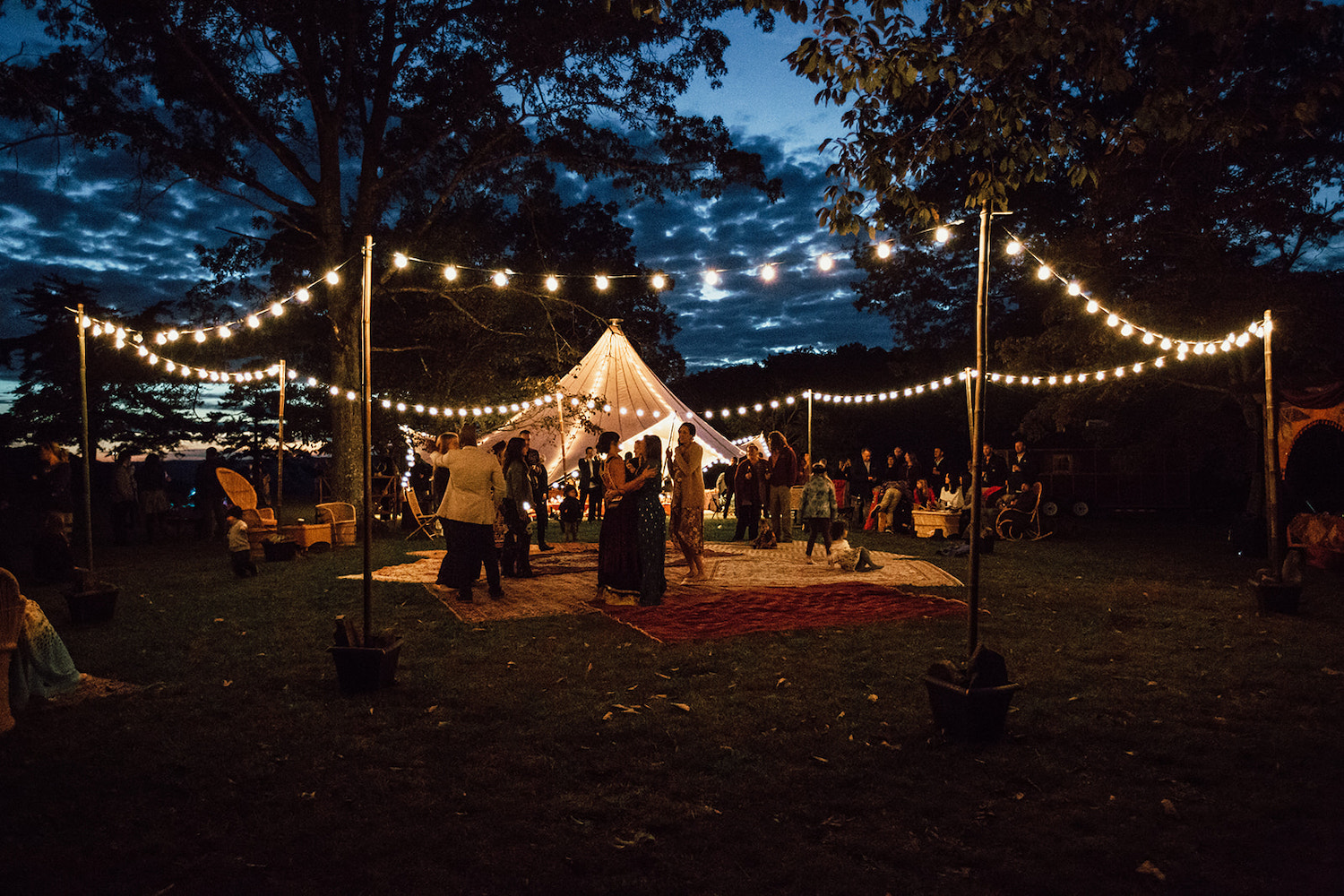 outdoor dance floor made of multiple Oriental rugs and white sting lights at Hemlock Falls wedding reception