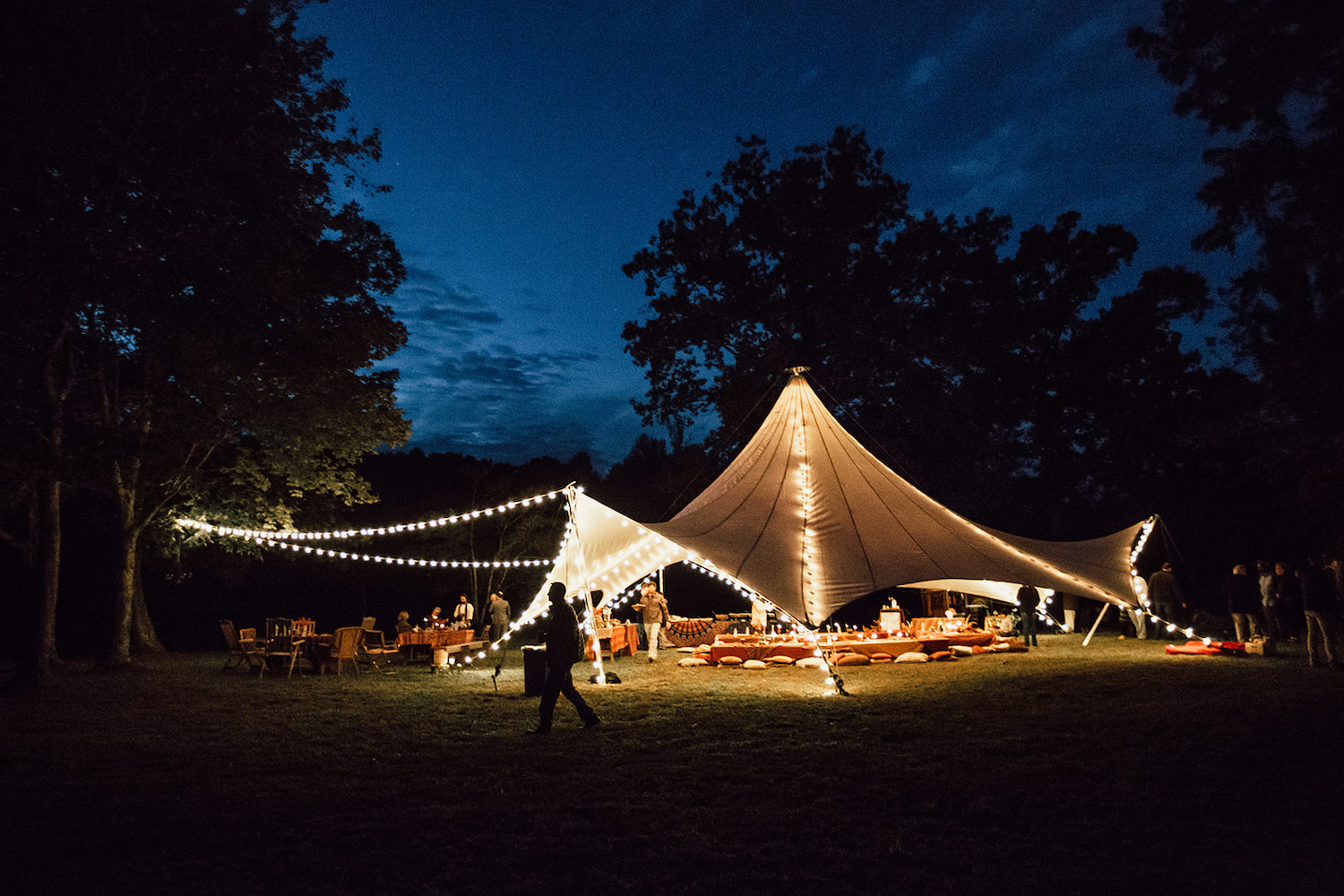 Bohemian festival wedding reception tent lit with white string lights