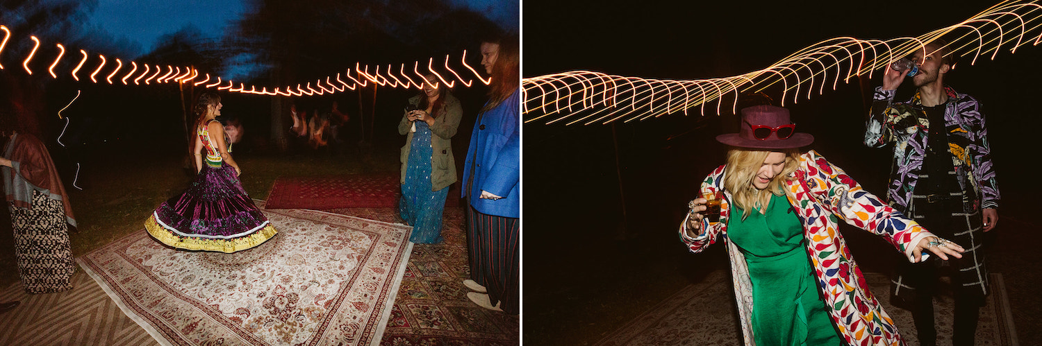 woman in green dress, red hat, and colorful jacket dances under string lights