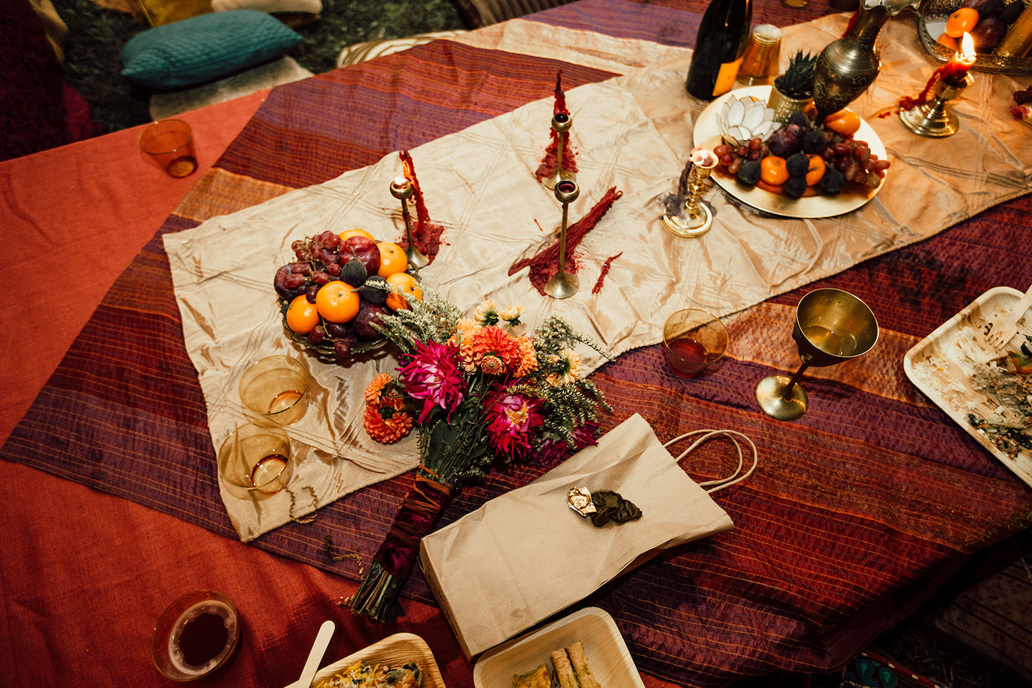 colorful red table cloth covered with platters of fruits and tall candlesticks and bright bouquet