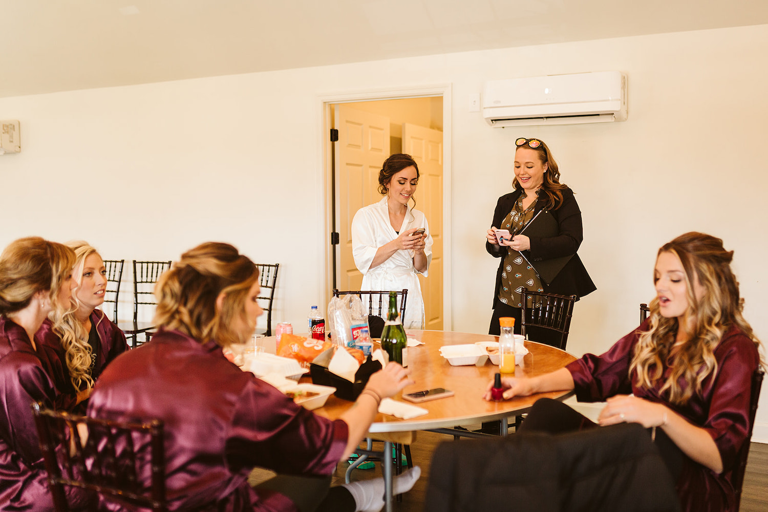 bride exchanges phone details with woman while bridesmaids talk at a round table