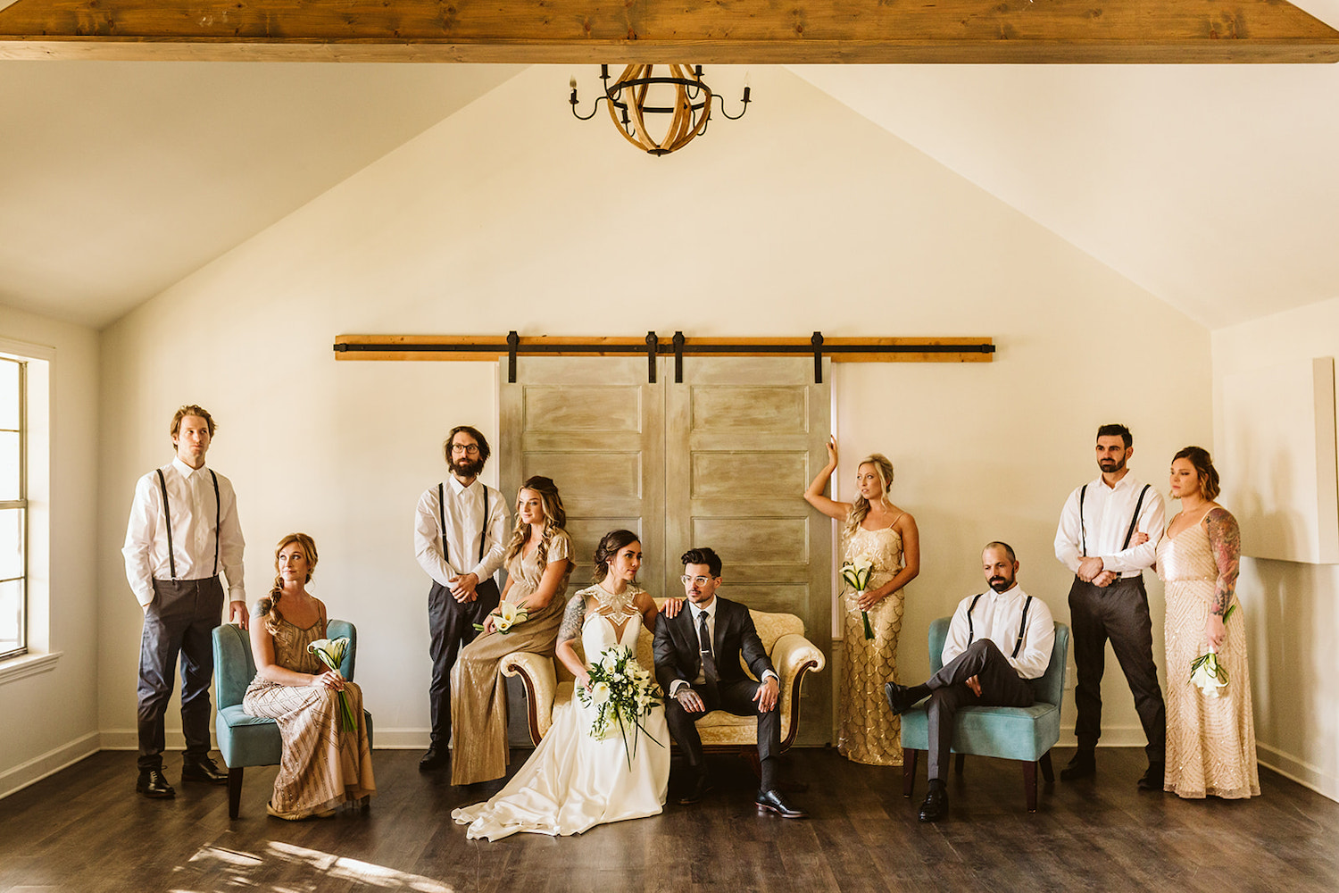 wedding party in a vogue group pose in high ceiling room in front of large barn doors