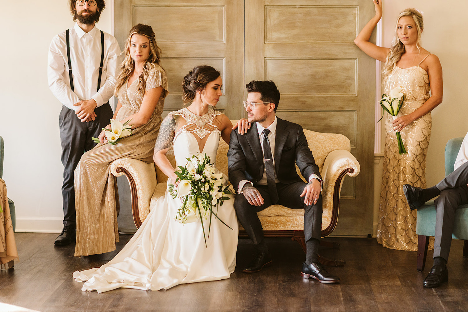 bride and groom sit on cream loveseat in front of large barn doors