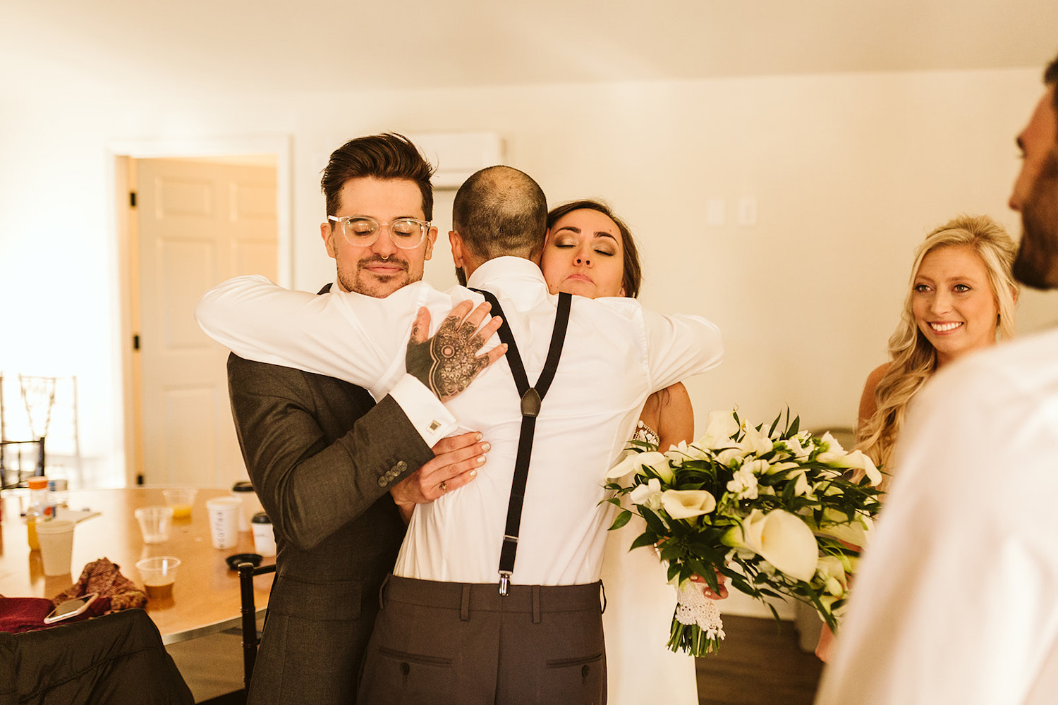 bride and groom hug groomsman