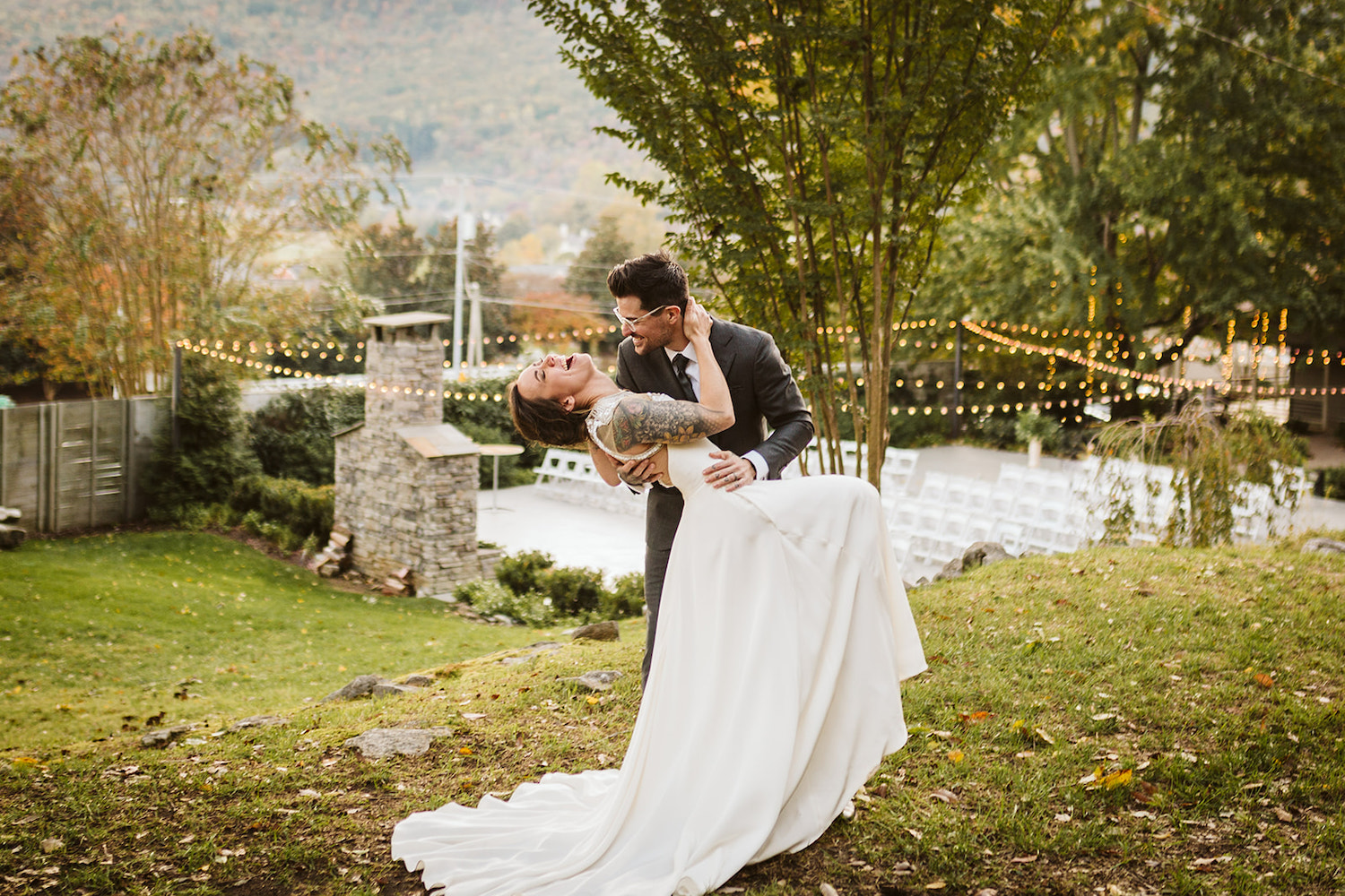 groom dips bride in a grassy lawn while they both laugh