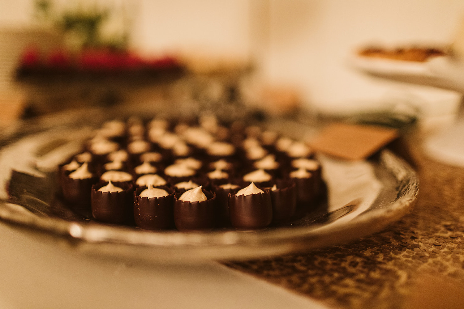 small chocolate cups with cream mousse sit on a silver platter