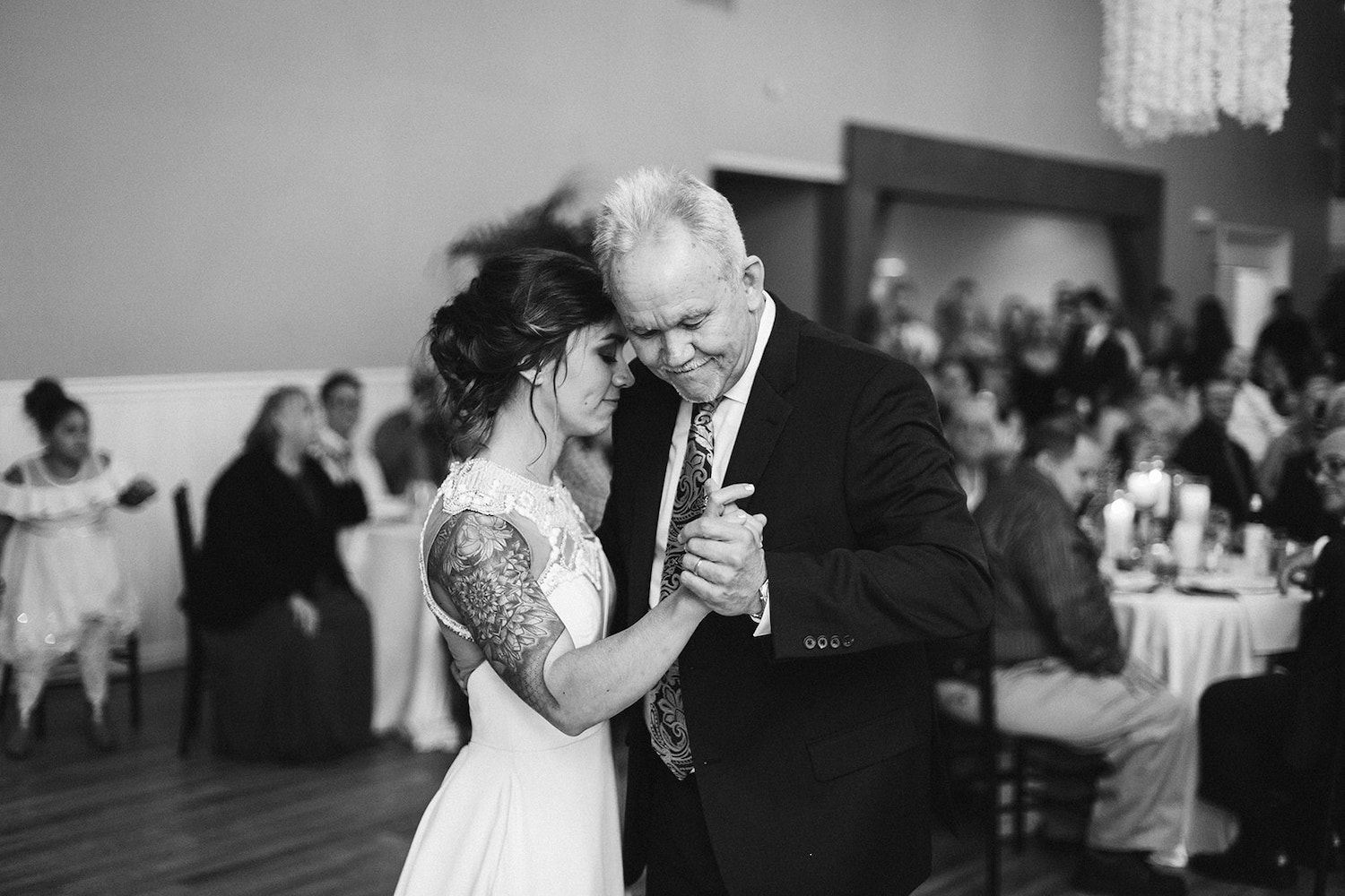 bride dances with her father while wedding guests watch