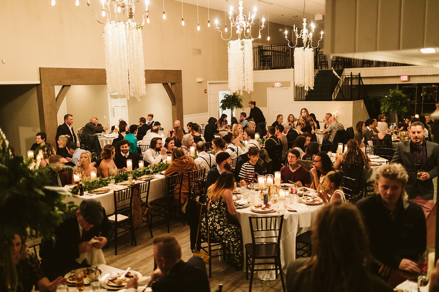 wedding guests enjoy a sit-down dinner under several candelabras