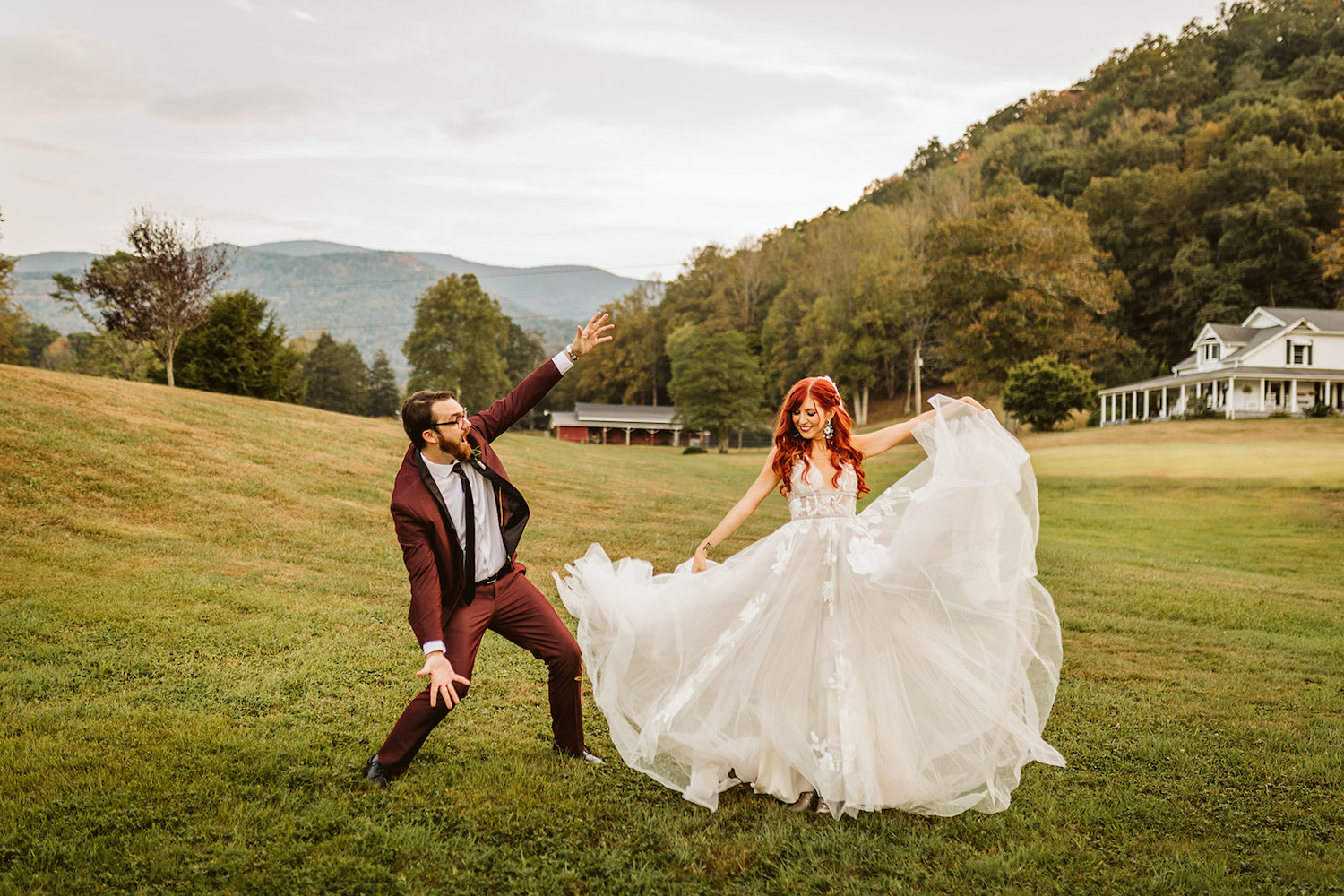 grooms holds his arms wide while bride spreads out the tulle skirt of her wedding gown at their Roan Mountain wedding