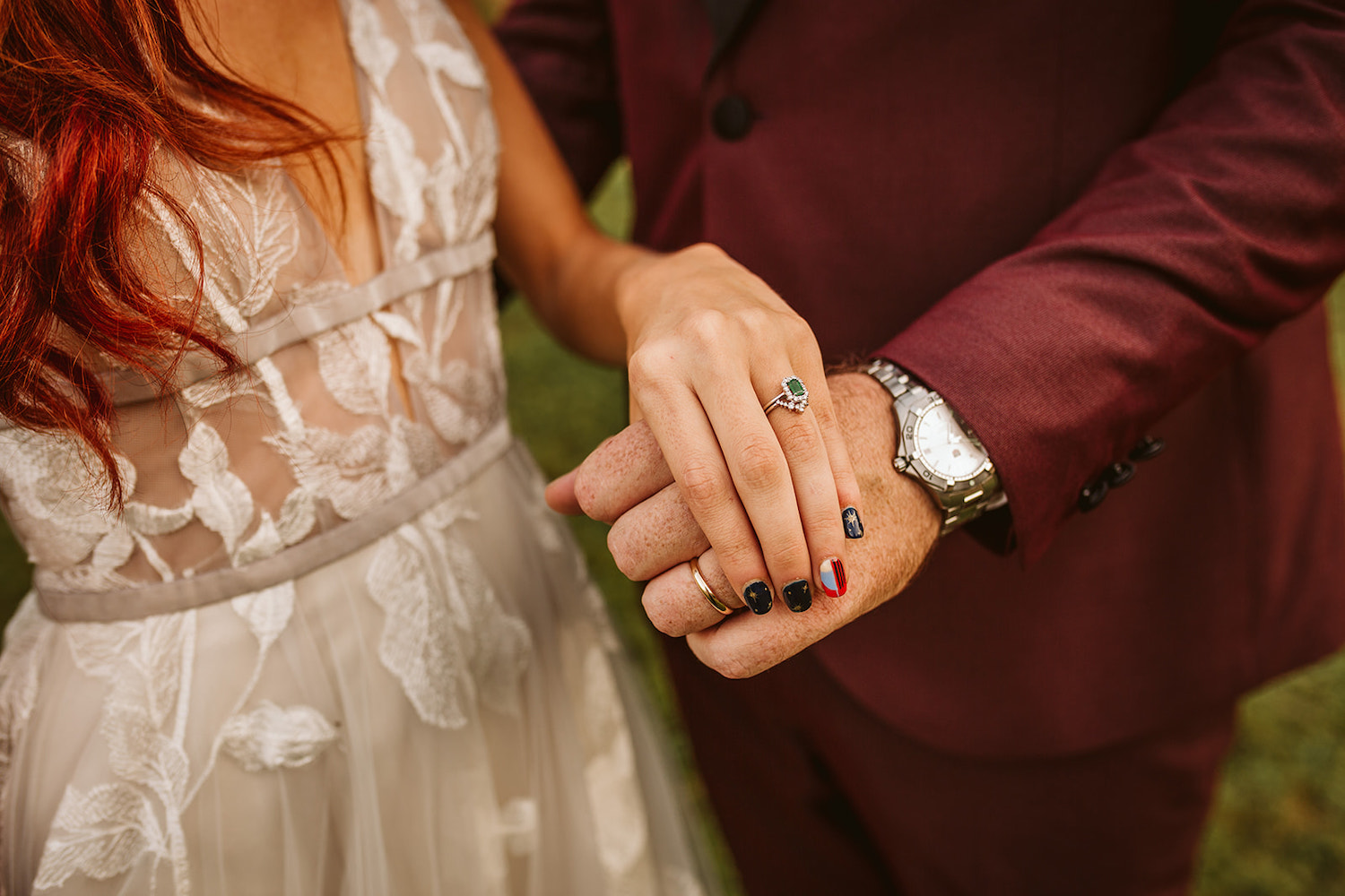 bride and groom hold hands to show off their wedding bands and her emerald engagement ring