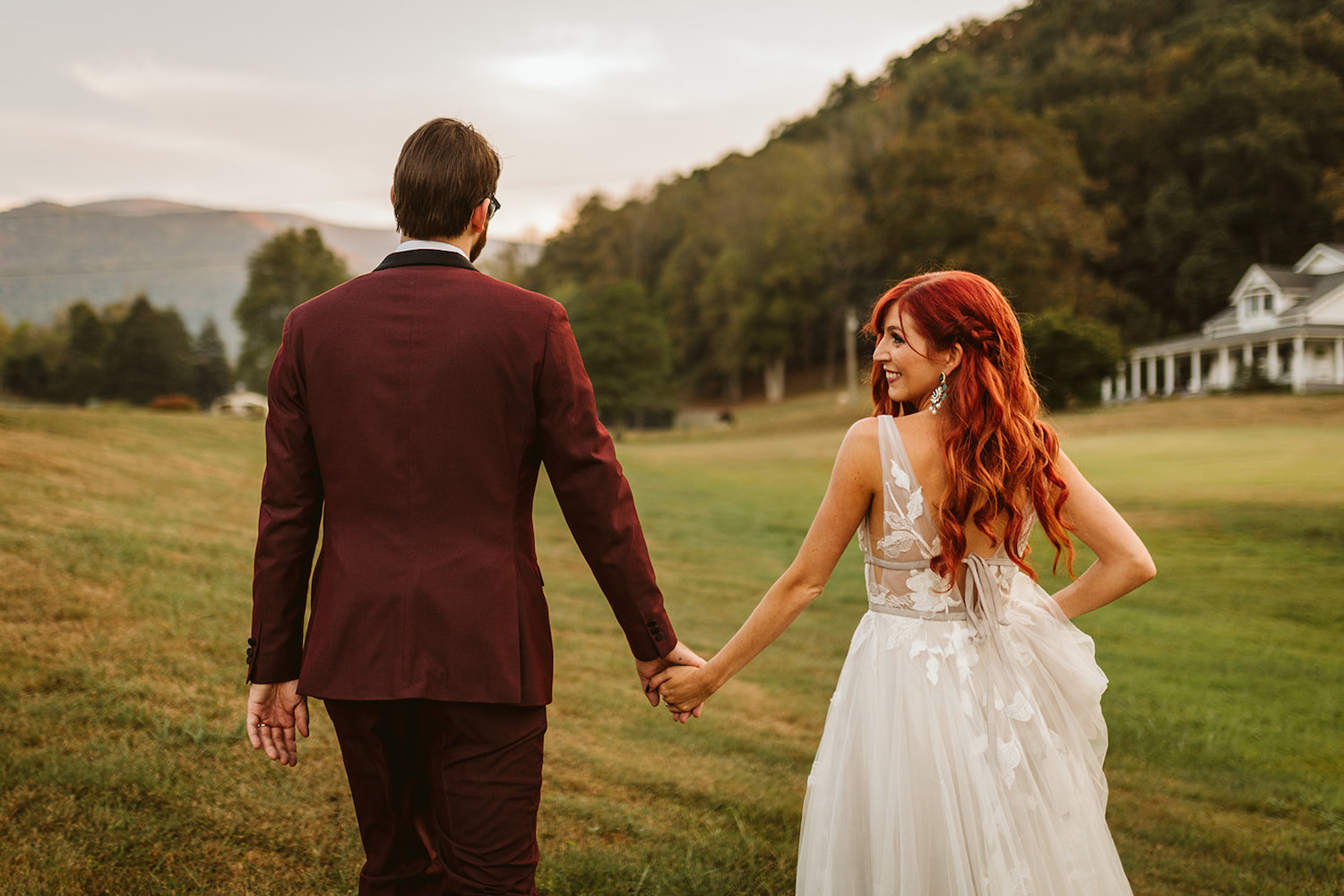 bride and groom hold hands and walk in a grass field at their Roan Mountain wedding in Cherokee National Forest