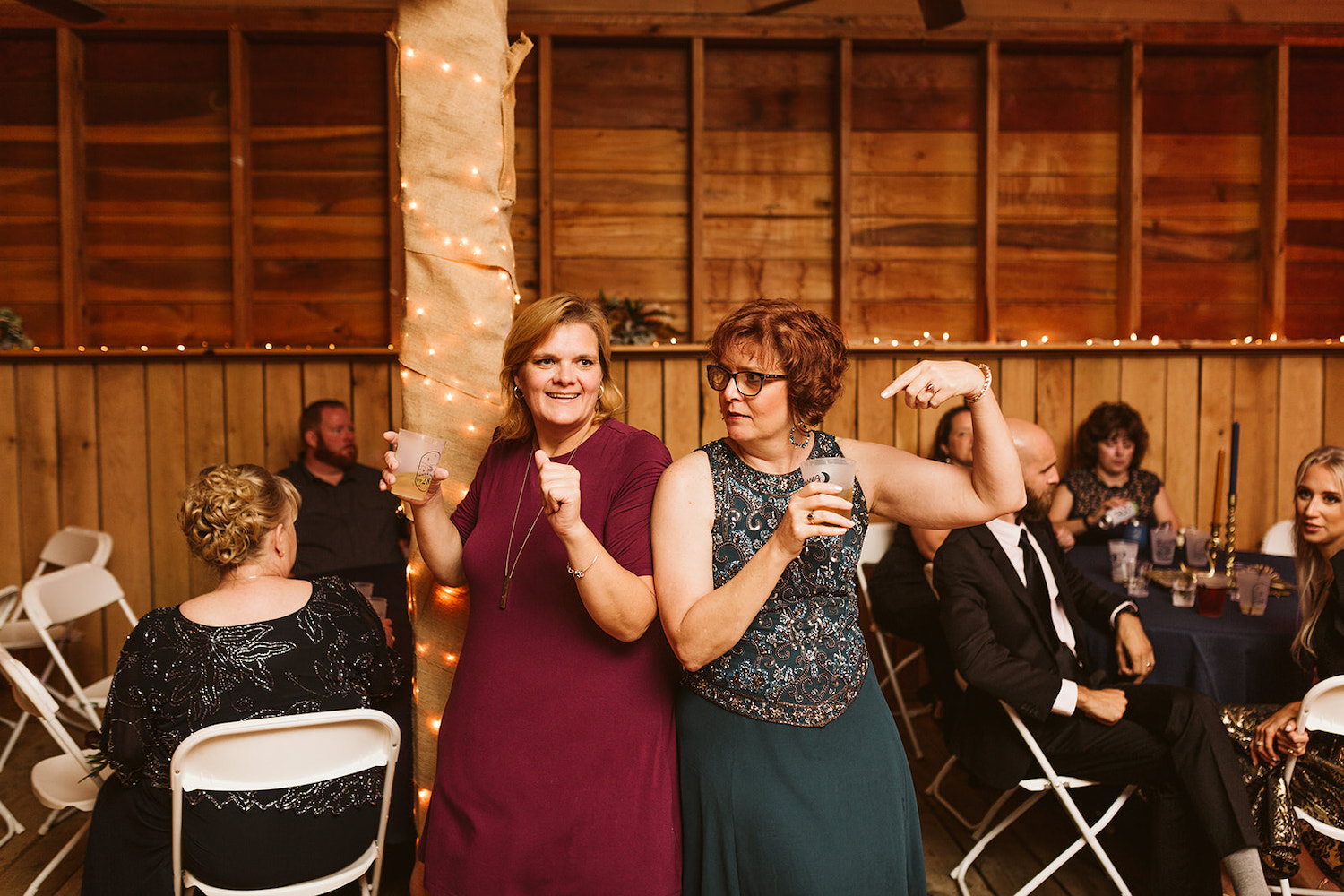 two women dance among wedding reception guests
