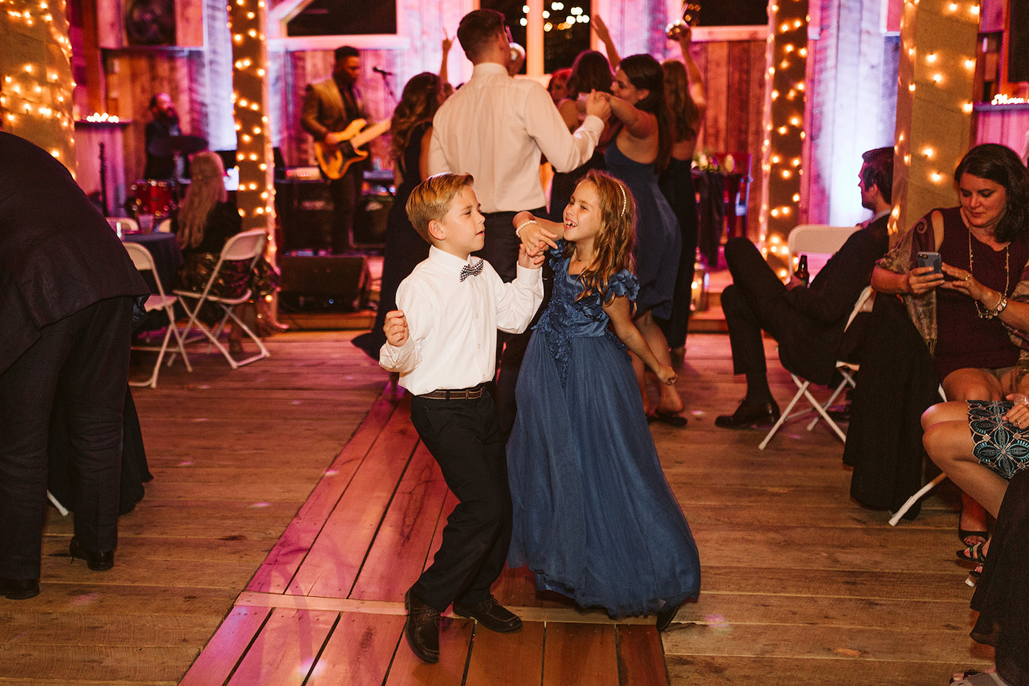 young boy and girl dance with other wedding guests