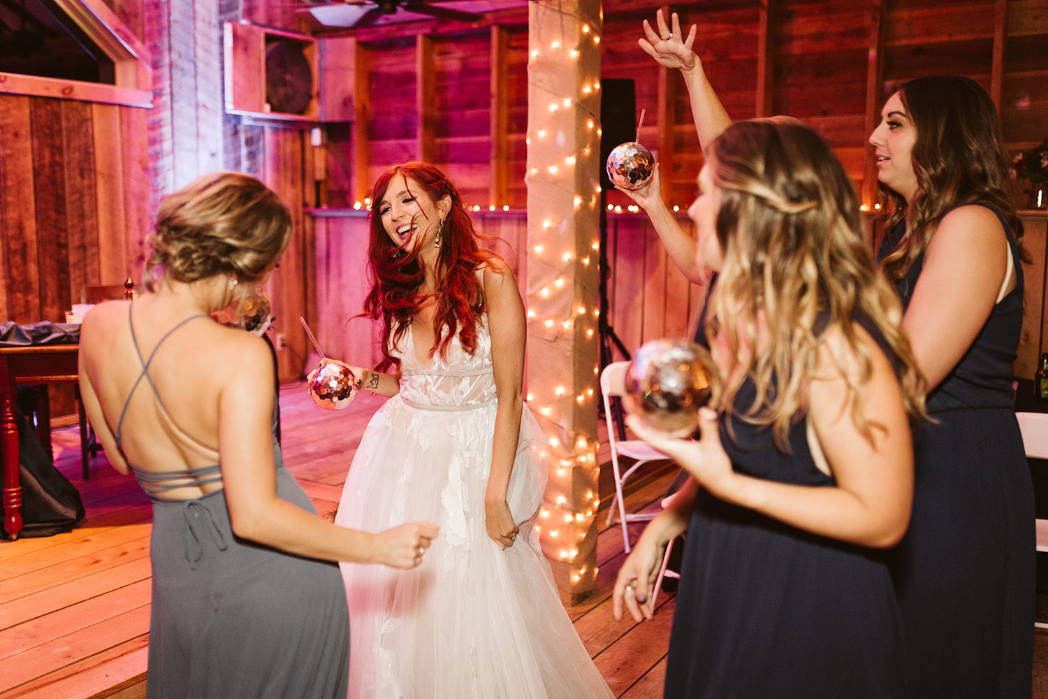 bride and bridesmaids hold drinks and dance together near band stage at her Roan Mountain wedding