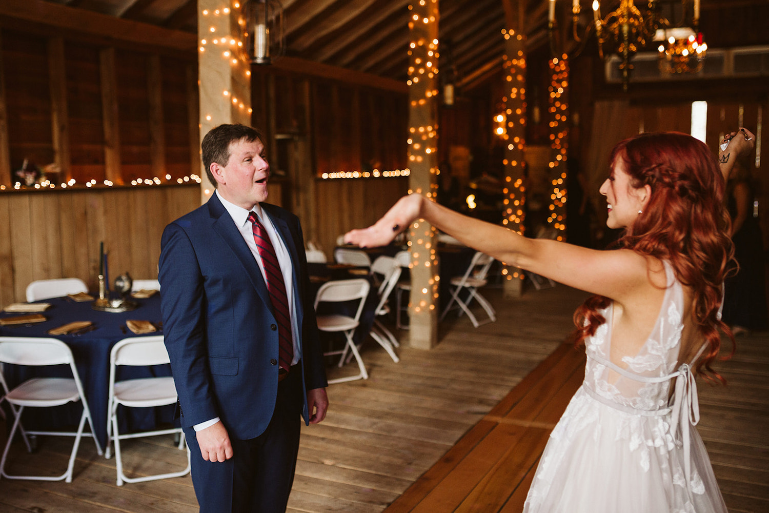 bride opens her arms wide as her father sees her in her wedding dress for the first time