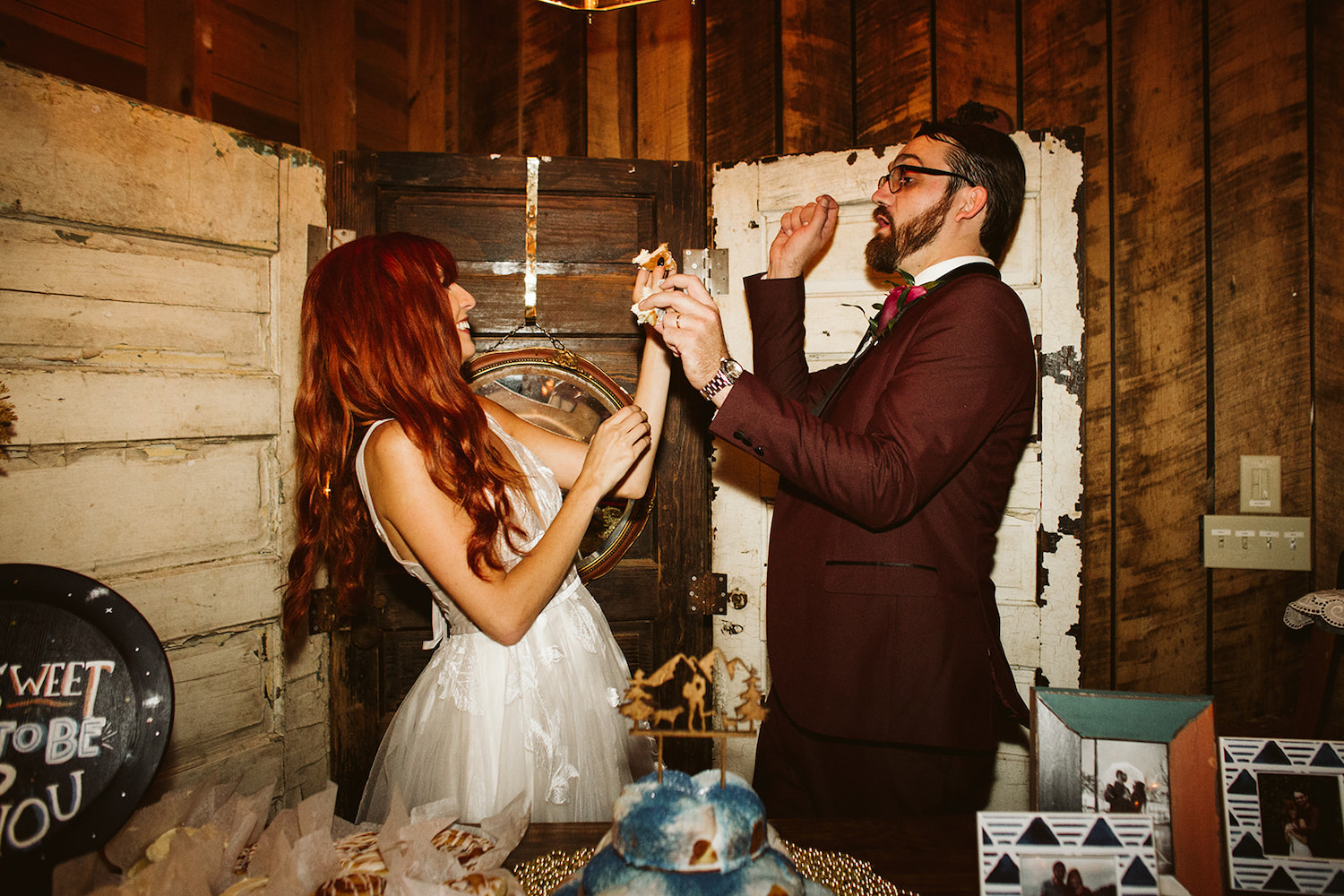 bride and groom feed each other wedding cake at their reception
