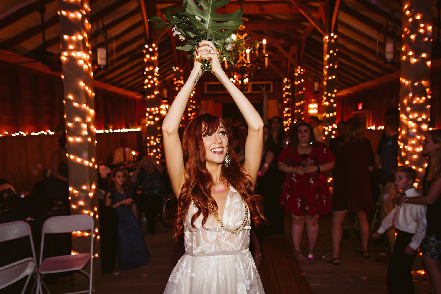 bride prepares to toss her bouquet over her head to waiting women