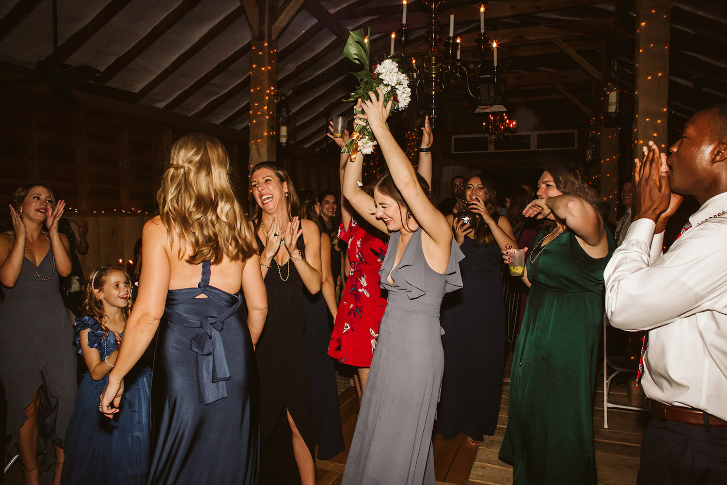 bridesmaid catches bouquet as other woman cheer and laugh