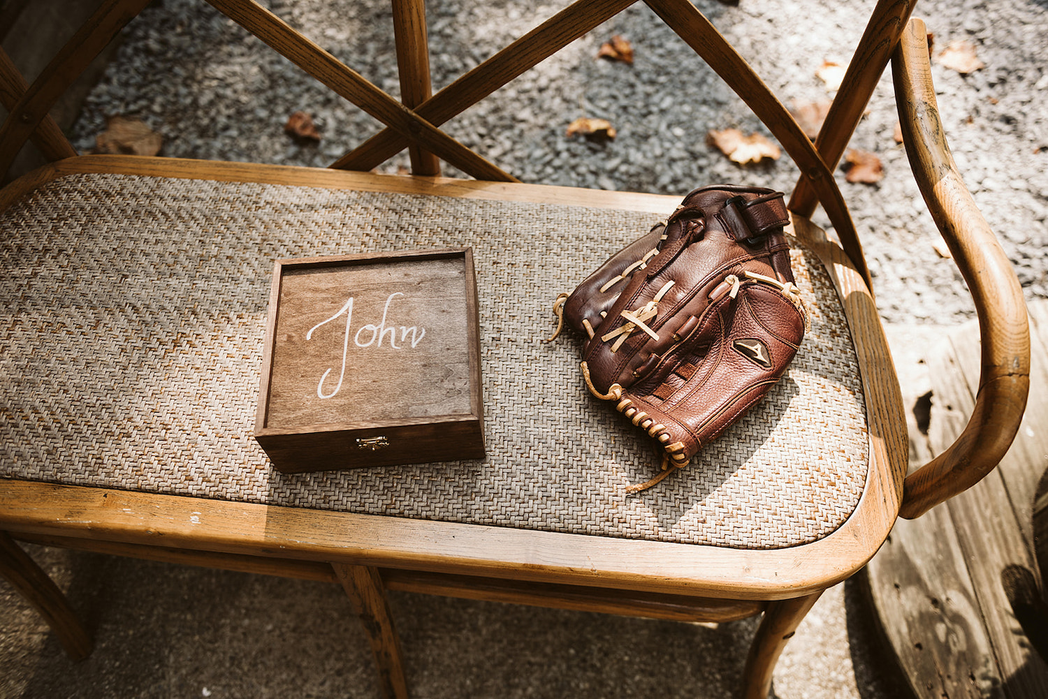 wooden box labeled John sits on a bench next to baseball glove