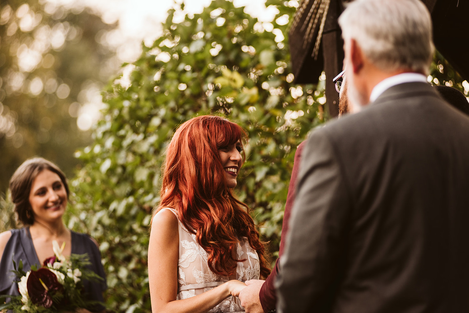 bride smiles at groom while he repeats his vows to her