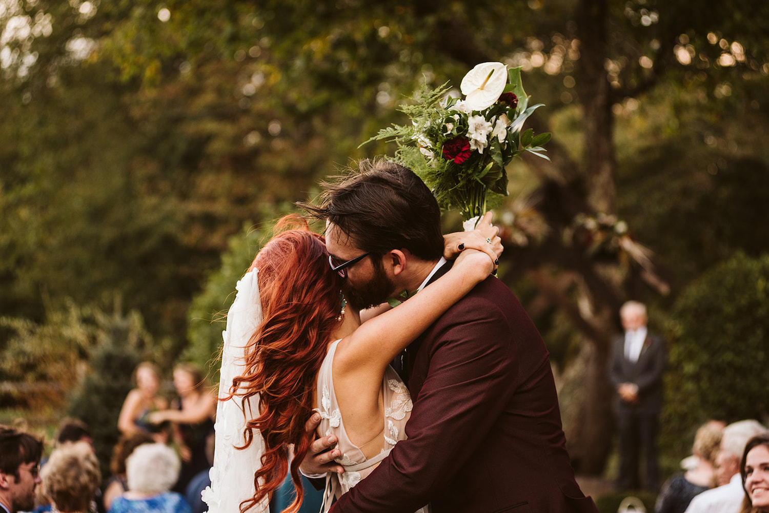 groom kisses bride's cheek as her red hair blows in the breeze