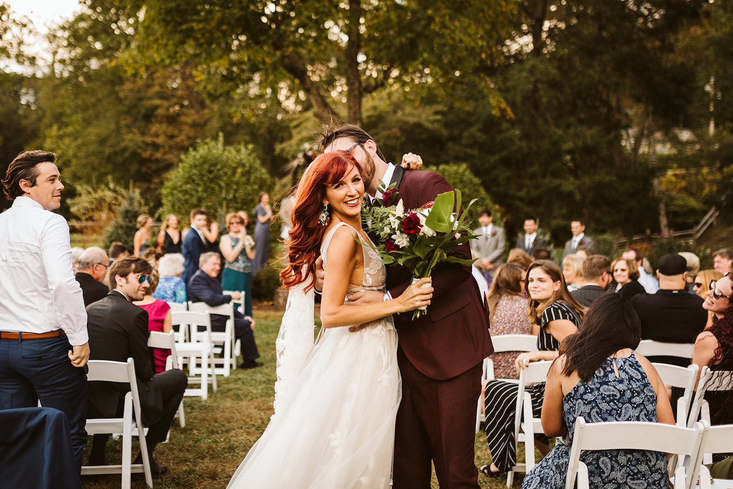 groom holds bride and kisses her at the end of the aisle at their Roan Mountain wedding in Cherokee National Forest