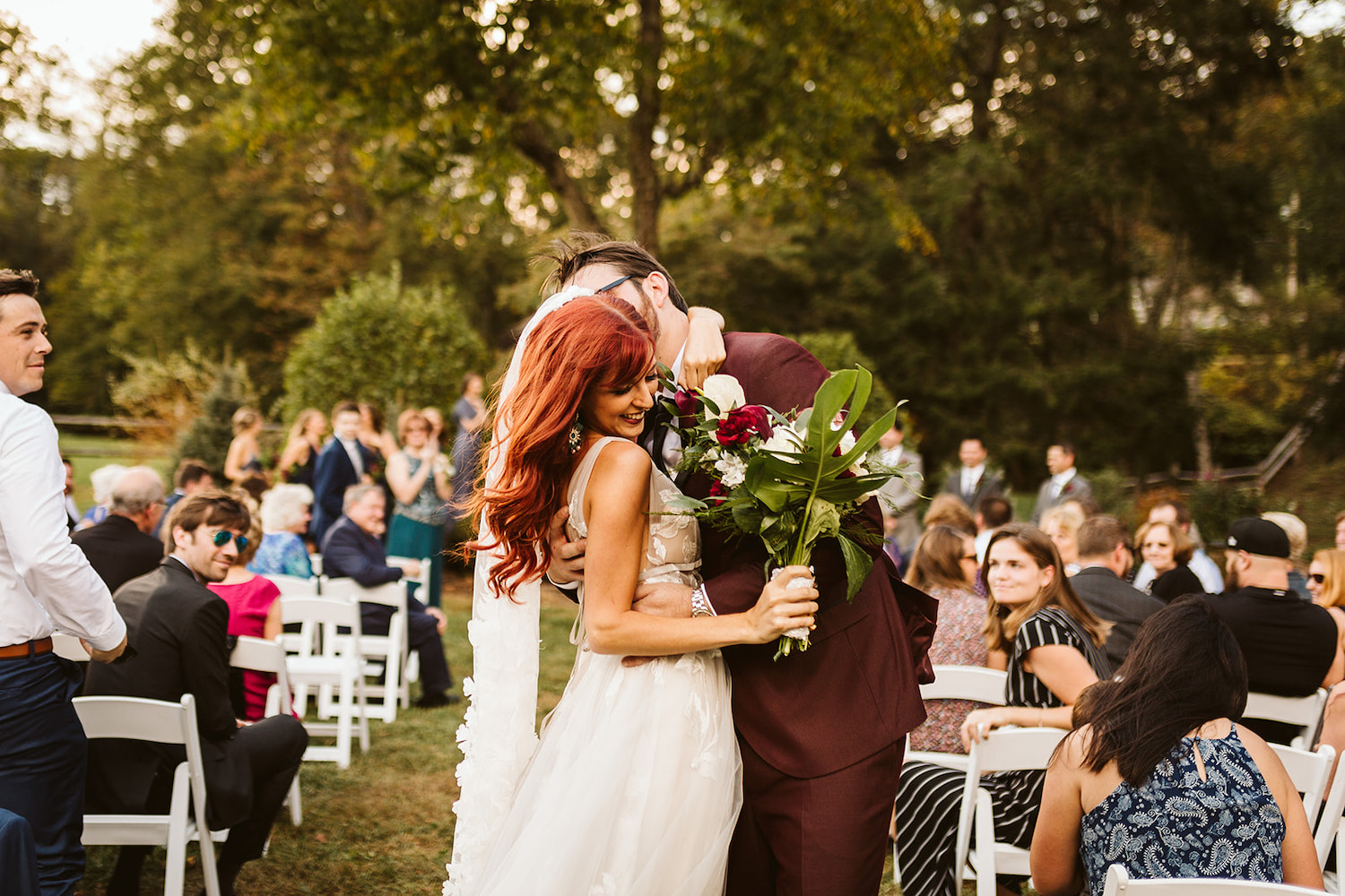 groom holds bride and kisses her at the end of the aisle at their Roan Mountain wedding in Cherokee National Forest