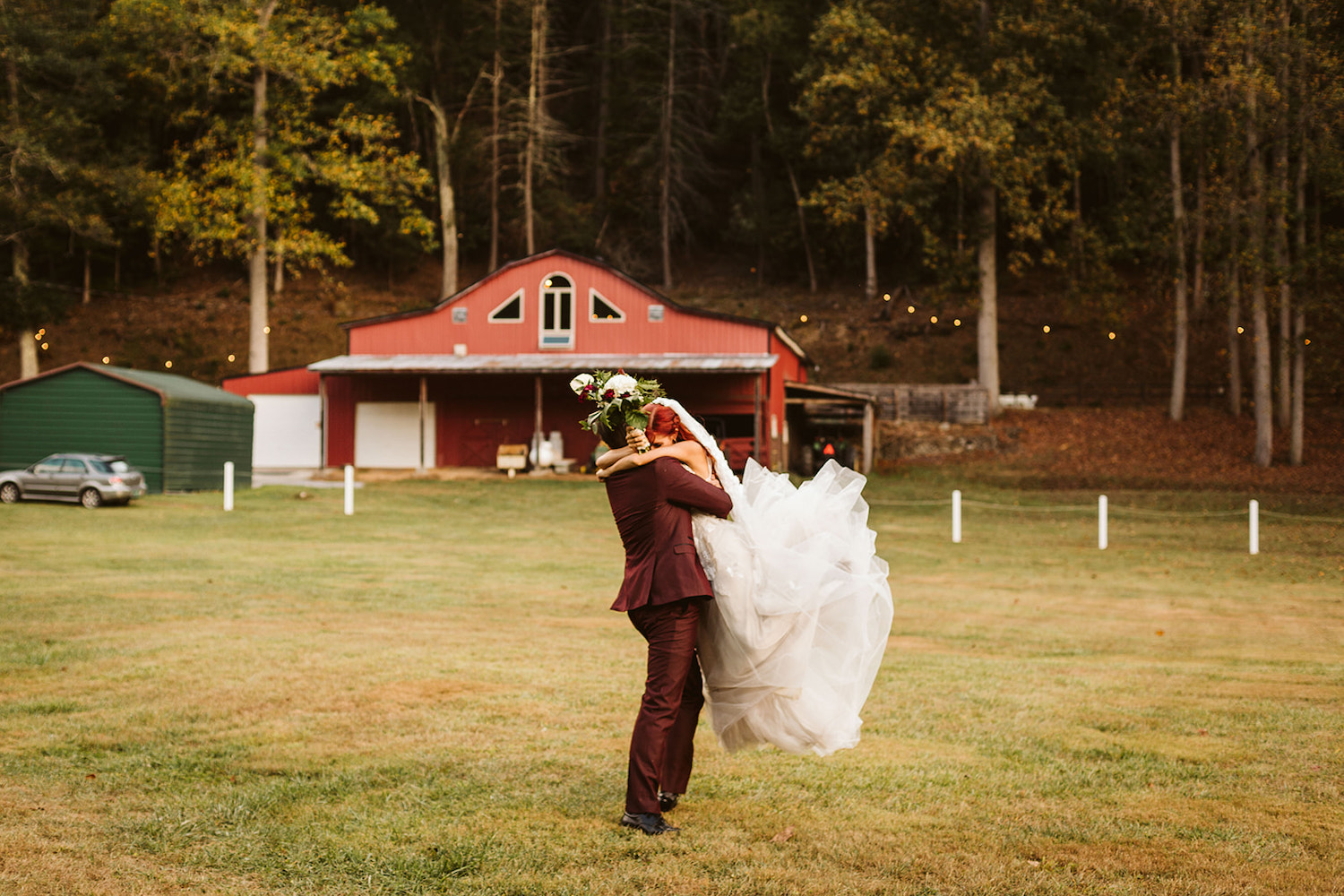 groom hugs bride and spins her in a grass field