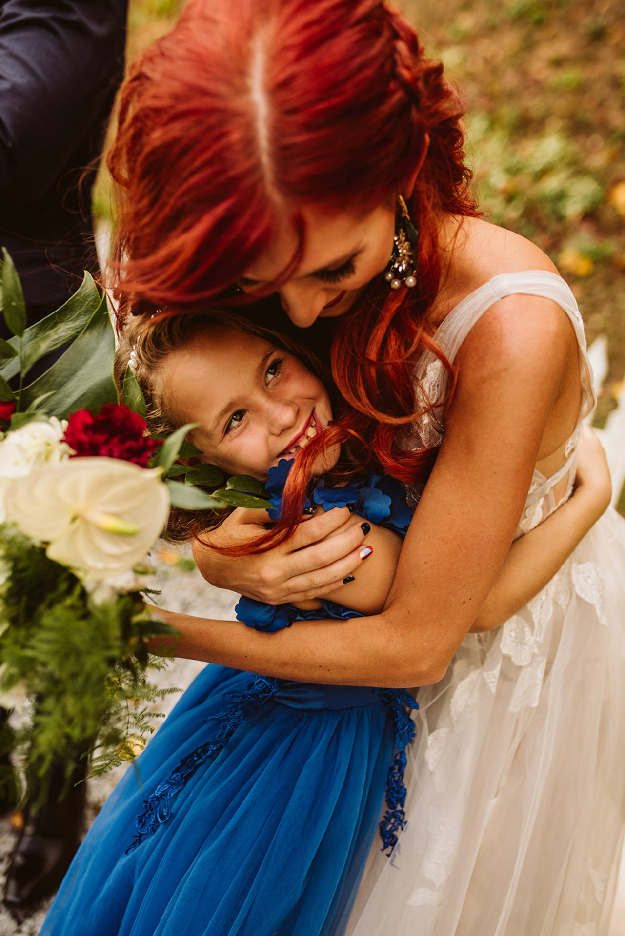 bride hugs young girl in blue dress