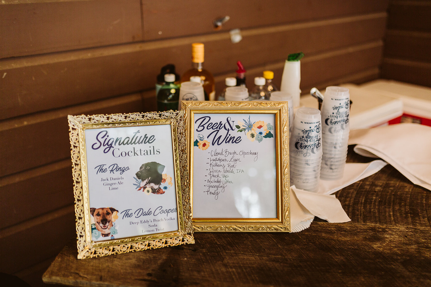 printed signs with beer and wine list and cocktails named after the couple's dogs sits in front of plastic cups