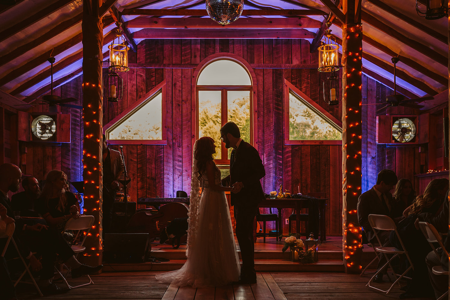 bride and groom share their first dance in a dimly lit barn interior