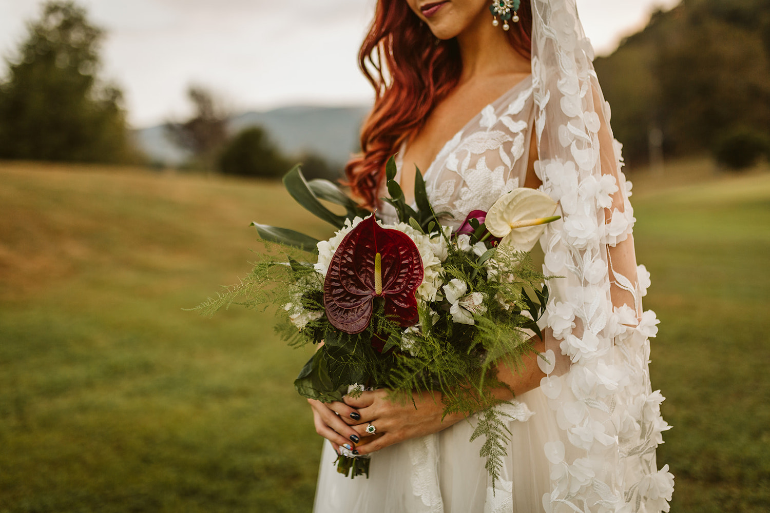 bride holds her bold red, white, and green bouquet
