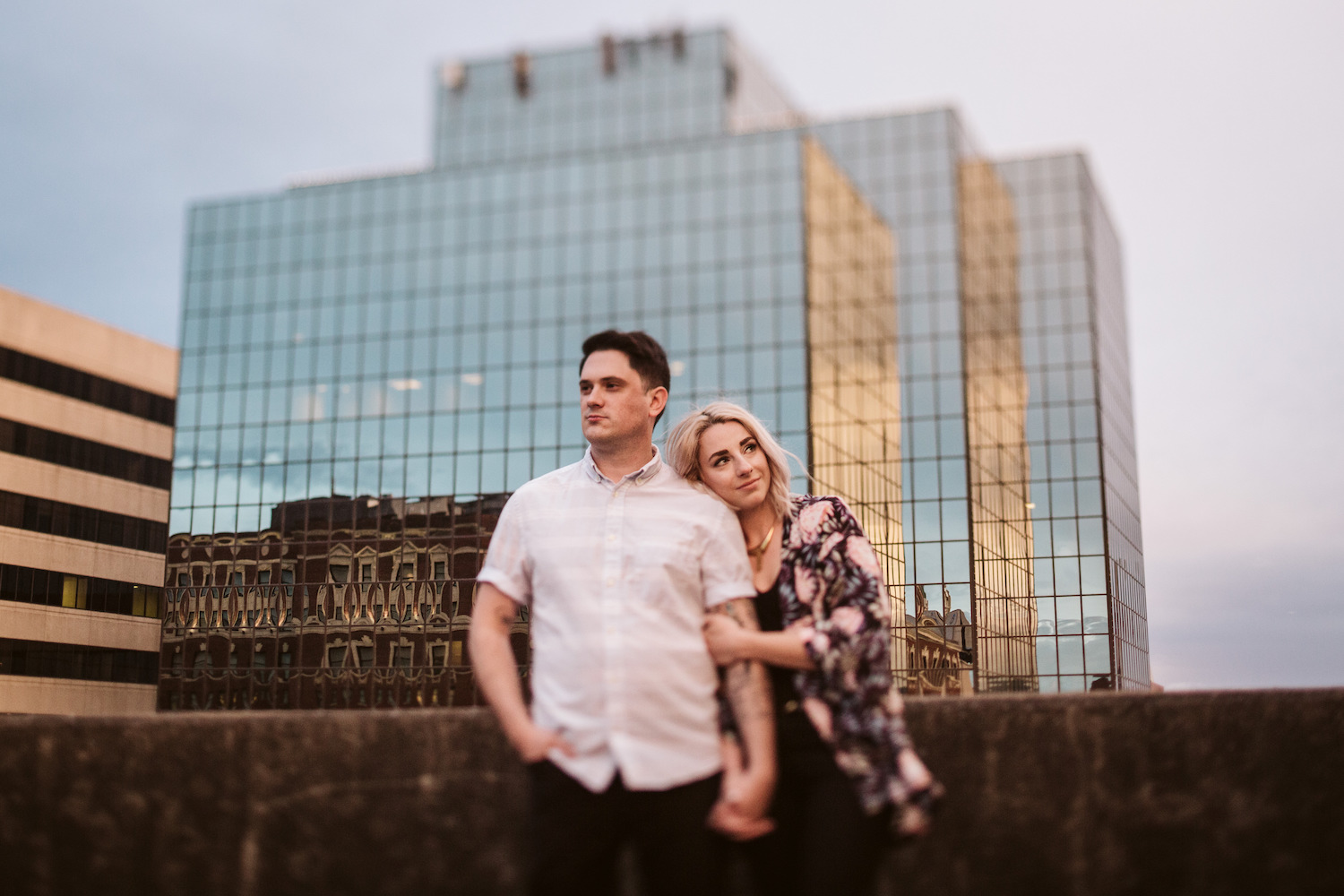 woman cuddles against man, holding his hand, her head on his shoulder, in downtown Chattanooga, TN