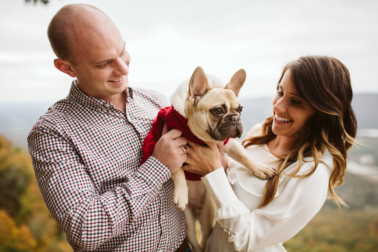 man and woman smile as they cuddle their French Bulldog on Sunset Rock on Lookout Mountain near Chattanooga, Tennessee