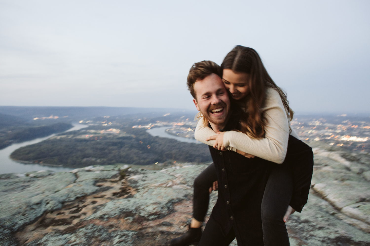 man carries woman on his back on Sunset Rock on Lookout Mountain near Chattanooga and they laugh