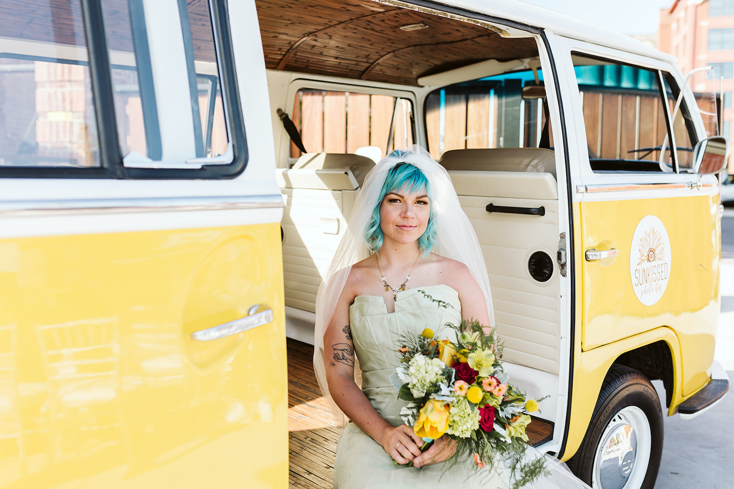 blue hair bride in strapless gown holding bright bouquet sits on floor of yellow vintage VW bus in Chattanooga Tennessee